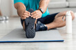 © Prostock-studio - Unrecognizable millennial muscular european man athlete doing leg exercises, stretching on mat