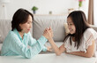 © Prostock-studio - Stressed little Asian girl arm wrestling with her grandmother, having conflict, fighting at home