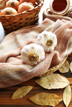 Closeup of garlic bulb on fabric with seasonings paprika powder onions and dried laurel. Seletive focus.