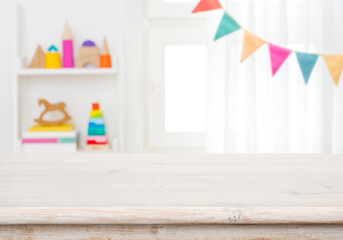Wall Mural - empty table with blurred children toy shelf and window background