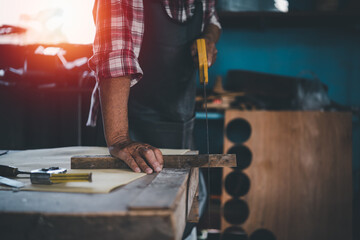 Wall Mural - Senior old carpenter working on wood craft at workshop to produce construction material or wooden furniture.