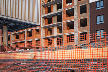 A residential building under construction behind a plastic fence on a winter day