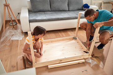 Wall Mural - Father and daughter assembling new furniture - moving in into a new home.