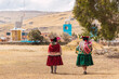 indigenous women walking dressed in typical dress made of alpaca fiber on a sunny day surrounded by clouds and a blue sky