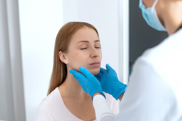 Family doctor in protective gloves touch neck of sick patient