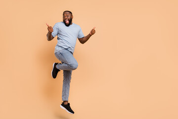 Wall Mural - Full length body size view of attractive cheerful cool guy jumping showing thumbup isolated over beige pastel color background