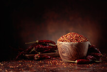 Chilli Flakes And Dried Chili Peppers On A Brown Background.