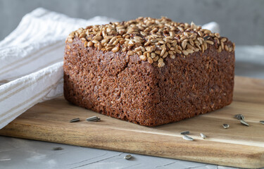 Wholemeal rye bread with sunflower seeds on cutting board.