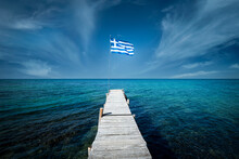 Greek Flag On A Beautiful Sunny Day At The End Of A White Wooden Pier. Corfu Greece