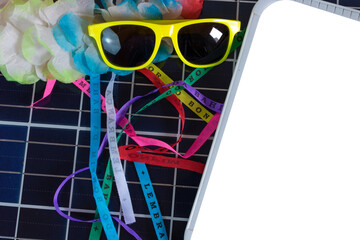 Wall Mural - Photovoltaic solar panel with Brazilian carnival elements. Solar plate with glasses, lucky bracelets, hat and carnival necklace isolated on white background.