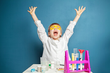 Wall Mural - Excited school girl doing science experiments smiling and laughing on blue background. Science and education concept