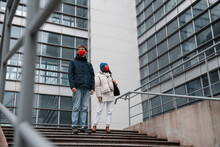 Young Male And Female In Masks Standing On Steps