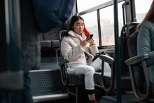 Asian Passenger Using Smartphone In Bus
