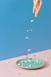 © Marc Tran/Stocksy - Hand and falling pills on pink table