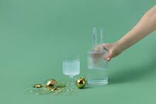 Decanter Near Glass Of Water And Golden Baubles