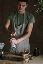 Young Man Grinding Coffee Beans For Brewing Coffee