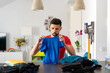 © Albert Martinez/Stocksy - man picking up a blue T-shirt, sorting clothes at home