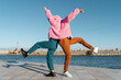 © Alba Vitta/Stocksy - Friends sharing colorful jacket while dancing