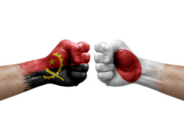 Two hands punch to each others on white background. Country flags painted fists, conflict crisis concept between angola and japan