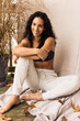 © Anna Tabakova/Stocksy - Woman in cozy sweatpants and sport bra smiling