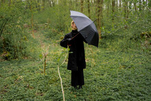 Woman Wearing Black Outfit Opening Umbrella In Forest 