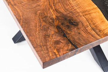 Poster - Close up of a Curly Bastogne Walnut wooden dining table with black epoxy resin and metal legs. White studio backdrop.