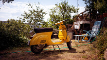 A Yellow Typical Italian Motorbike In A Backyard 