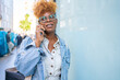 © Luis Velasco/Stocksy - Black Woman With Glasses On A Call On The Street.