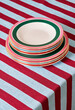 © Sergey Melnikov/Stocksy - Stack of plates on striped tablecloth
