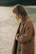 © Olga Moreira/Stocksy - Woman in overcoat on the winter beach