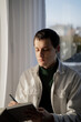 © Olga Kozicka/Stocksy - Man Journaling By Window With AirPods In His Ears