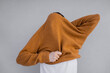 © Olga Kozicka/Stocksy - Pulling Sweater Over Head