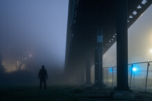 A Man Standing Under A Bridge At Night