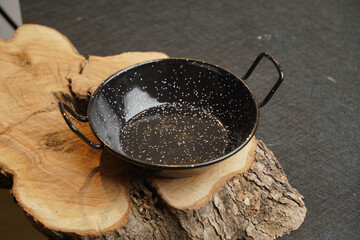 Sticker - A black pan with white spots on a wooden surface