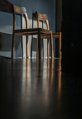 Wall Mural - Two wooden chairs standing front of green cement wall at an empty room through which a ray of light passes. Space for text, Selective focus.