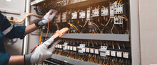 Electricity And Electrical Maintenance Service, Engineer Using Measuring Equipment Tool Checking Electric Current Voltage At Circuit Breaker Terminal And Cable Wiring Main Power Distribution Board.
