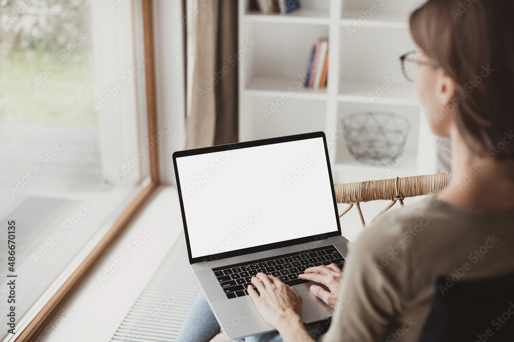 Young woman using laptop computer with white mockup screen at home ...