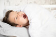 © Tatsiana - Cute little boy wake up in his comfortable bed in the morning and yawns. Good morning