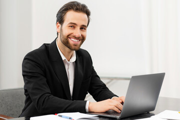 Happy smiling business man working from office. Successful male sitting at the desk, using laptop, develop a project. Workplaces concept