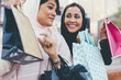 © oneinchpunch - Two arabian girls spending time together outdoor making activities. Young women making shopping in Dubai