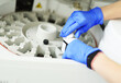 laboratory assistant in blue rubber gloves adds a reagent to the centrifuge of a modern biochemical analyzer.