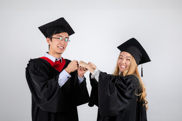 Wall Mural - Graduate students knock knuckles happy in gowns and mortarboards