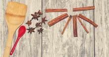Cinnamon, Anise, Star Anise And A Porcelain Tea Spoon Lie On A Wooden Surface.