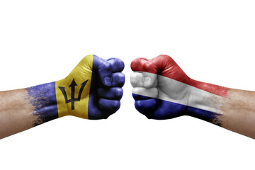 Two hands punch to each others on white background. Country flags painted fists, conflict crisis concept between barbados and netherlands