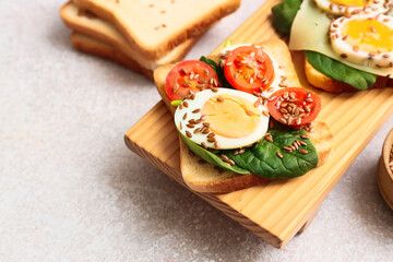 Board with tasty toasts on light background