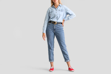 Wall Mural - Fashionable young woman in stylish jeans clothes on light background