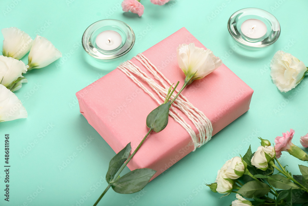 Beautiful gift box, candles and flowers on color background