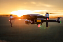 Unmanned Quadcopter In Flight With A Digital Camera At Sunset. Drone Silhouette At Sunset