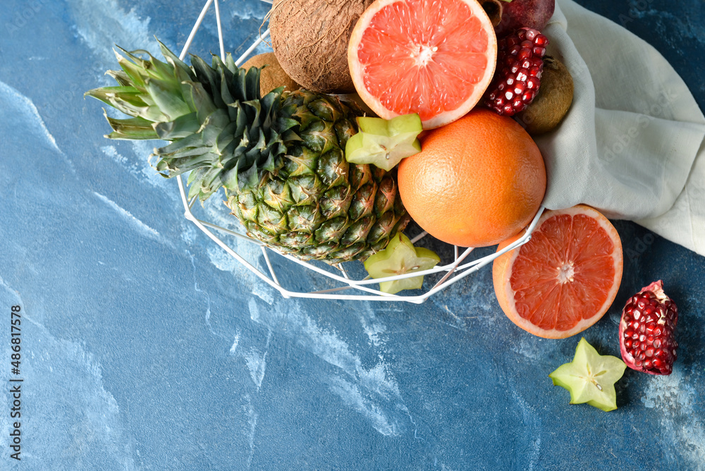 Basket with fresh juicy fruits on color background
