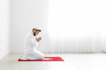 Praying young Muslim man at home